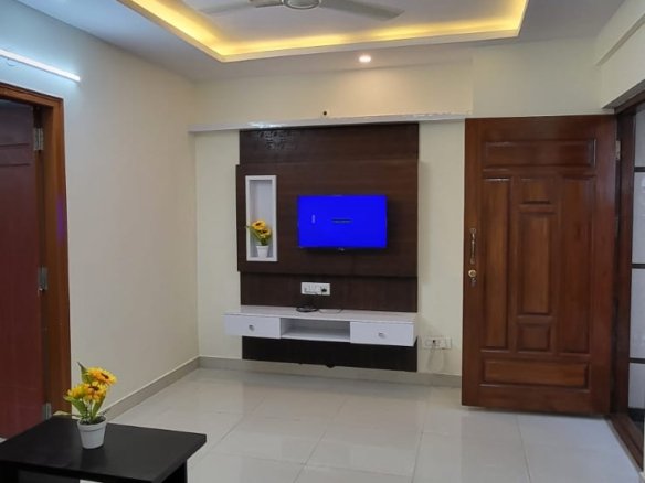 furnished hall with table sofa and tv unit in 1bhk fully furnished flat