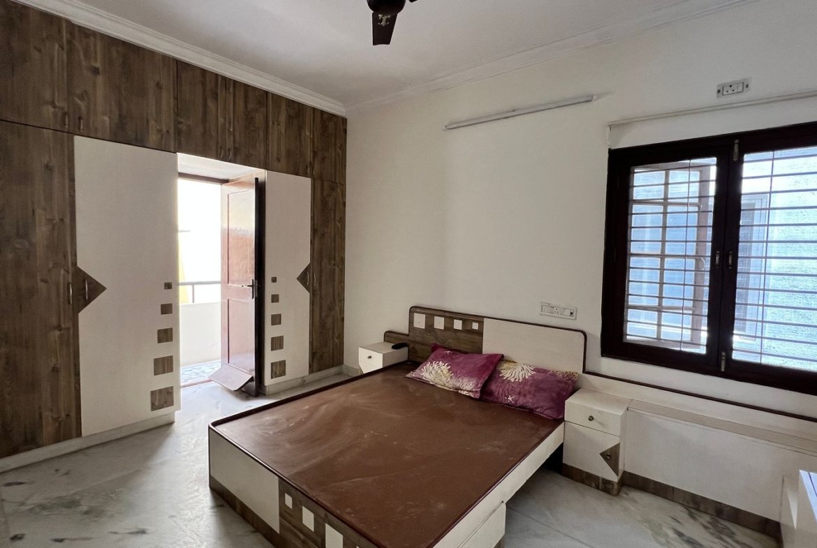 2BHK apartment master bedroom with double bed, wardrobe and window in HSR Layout, Bangalore – Renthouzz