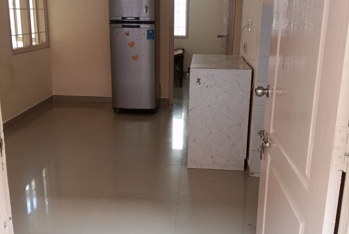 Spacious living room with sofa setup, TV, and natural sunlight in 2BHK flat Electronic City