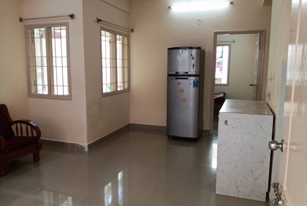 Spacious living room with sofa setup, TV, and natural sunlight in 2BHK flat Electronic City
