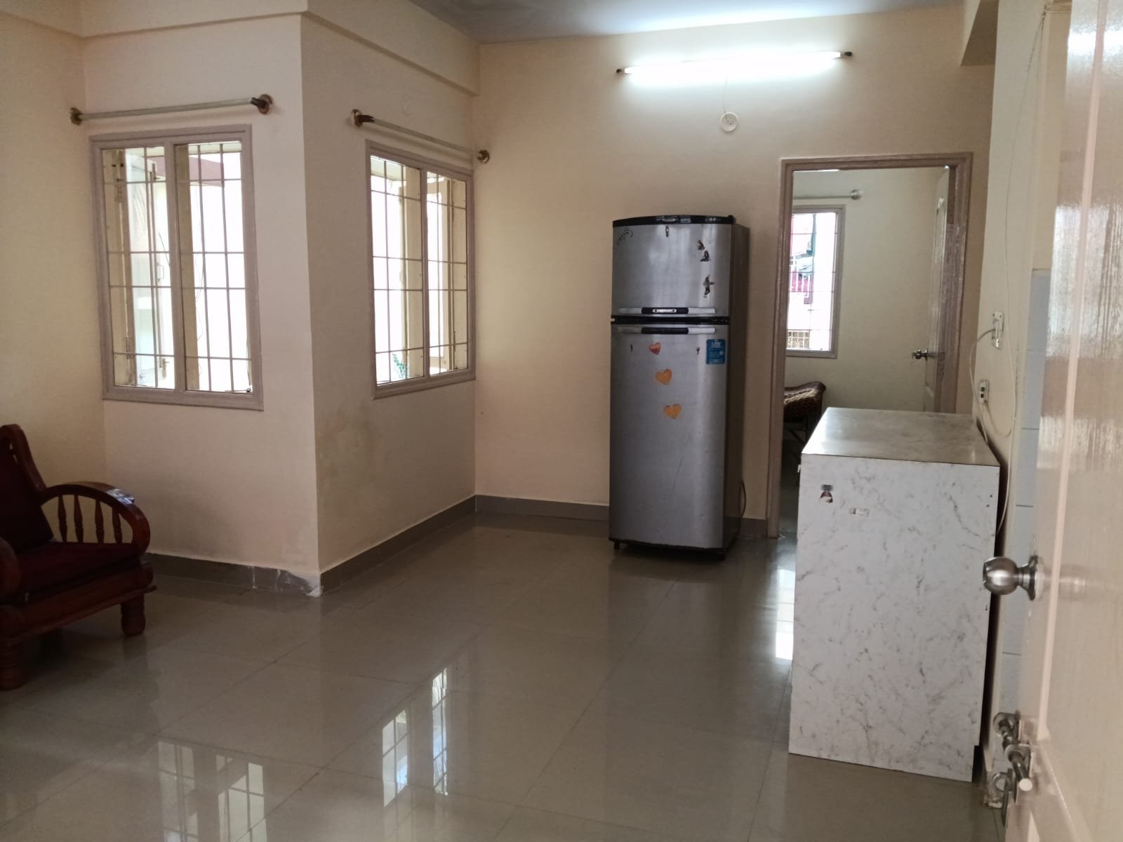 Spacious living room with sofa setup, TV, and natural sunlight in 2BHK flat Electronic City