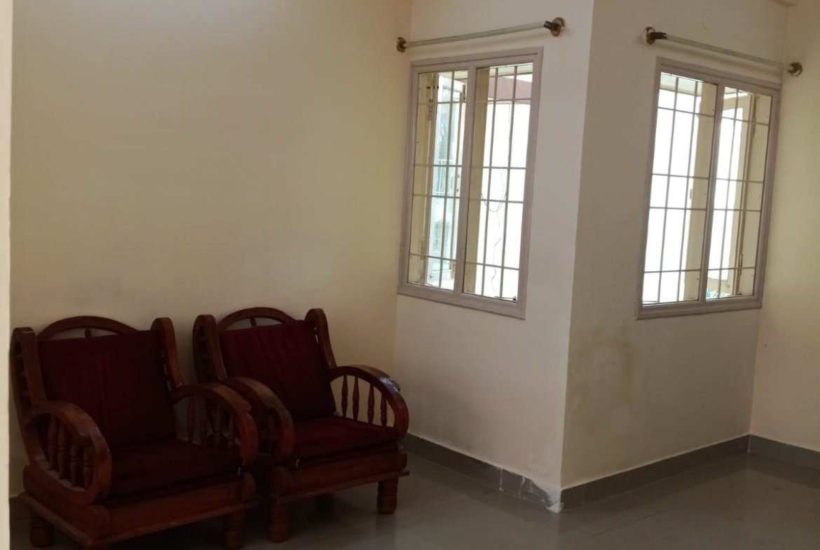 Spacious living room with sofa setup, TV, and natural sunlight in 2BHK flat Electronic City