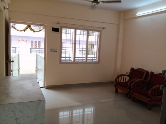 Spacious living room with sofa setup, TV, and natural sunlight in 2BHK flat Electronic City