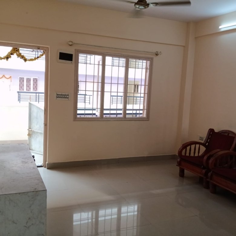 Spacious living room with sofa setup, TV, and natural sunlight in 2BHK flat Electronic City