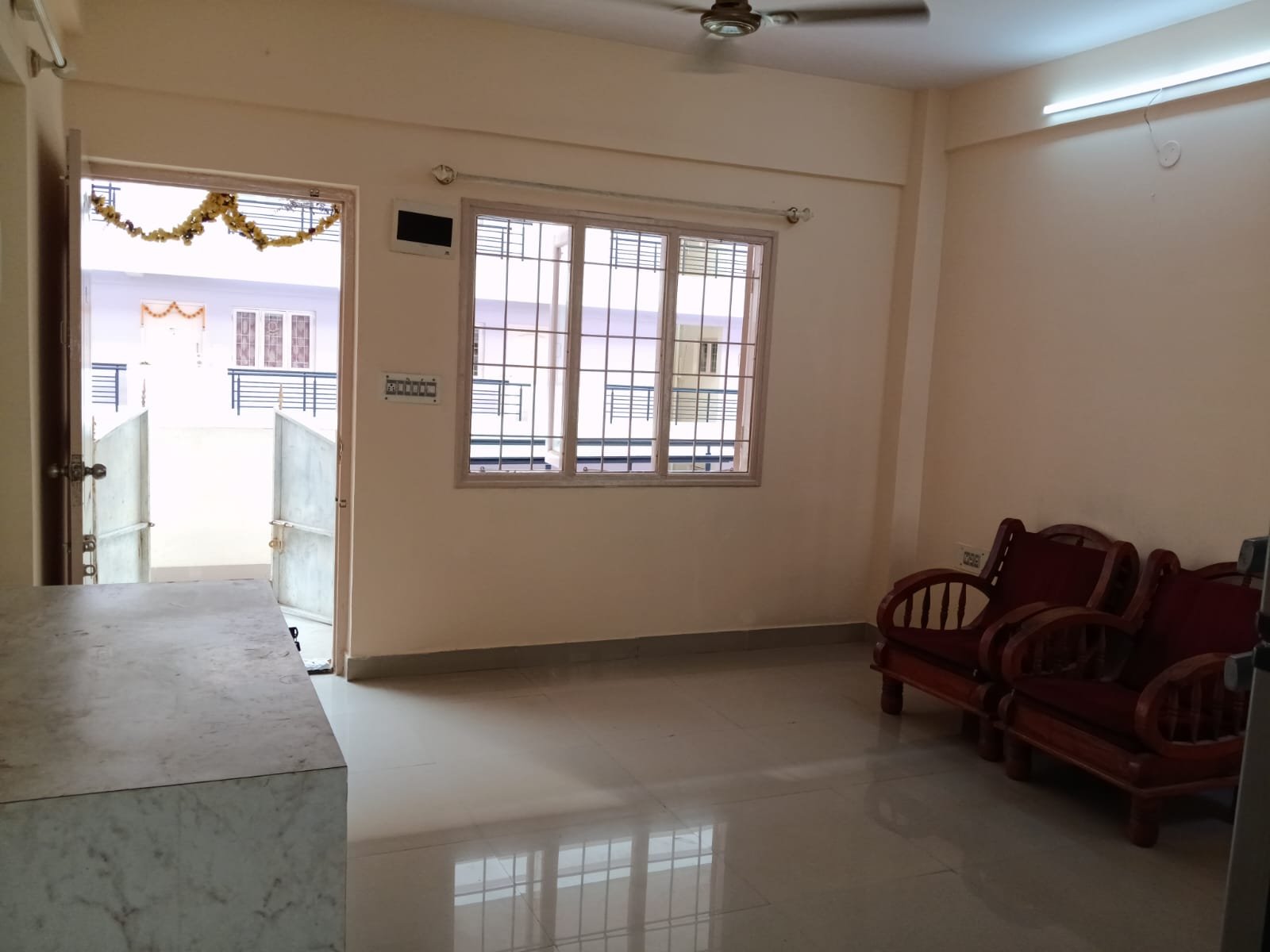 Spacious living room with sofa setup, TV, and natural sunlight in 2BHK flat Electronic City