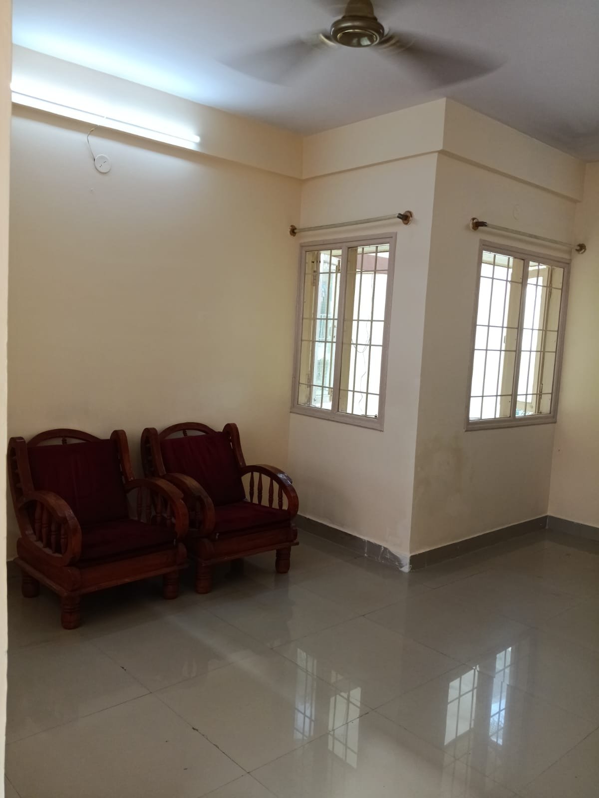 Spacious living room with sofa setup, TV, and natural sunlight in 2BHK flat Electronic City