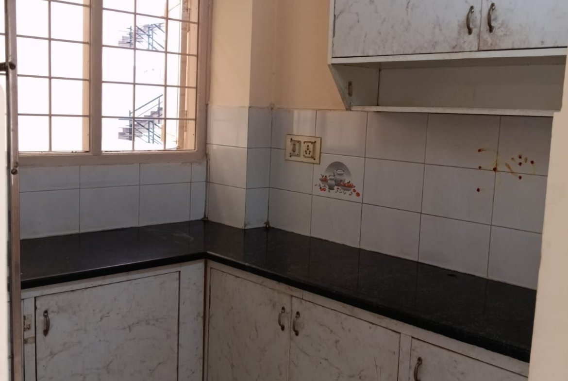 Modular kitchen with storage cabinets and utility area in Electronic City apartment