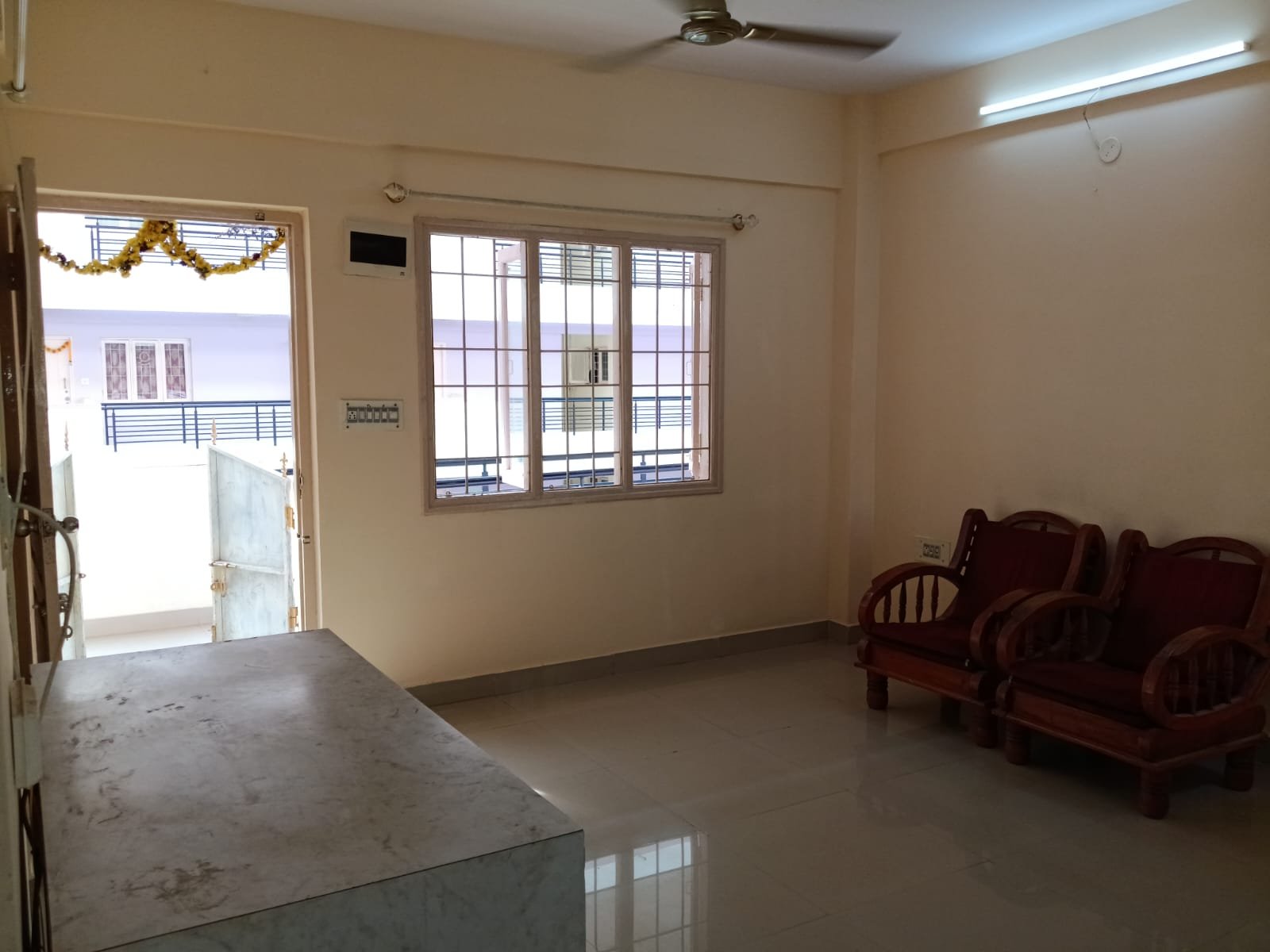 Spacious living room with sofa setup, TV, and natural sunlight in 2BHK flat Electronic City